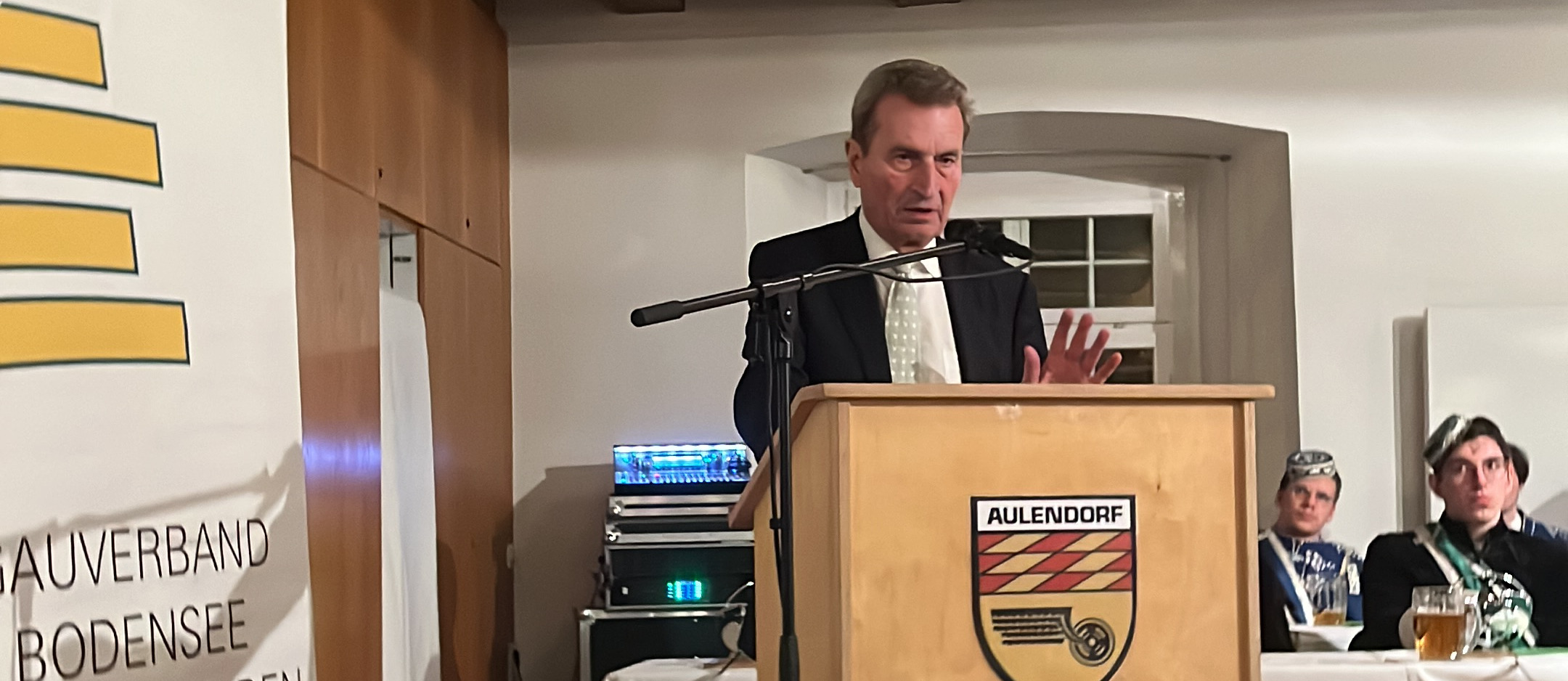 Festredner Günther Oettinger am Rednerpult mit Aulendorfer Stadtwappen, im Hintergrund das Banner „Gauverband Bodensee“ und Chargierte in Couleur.